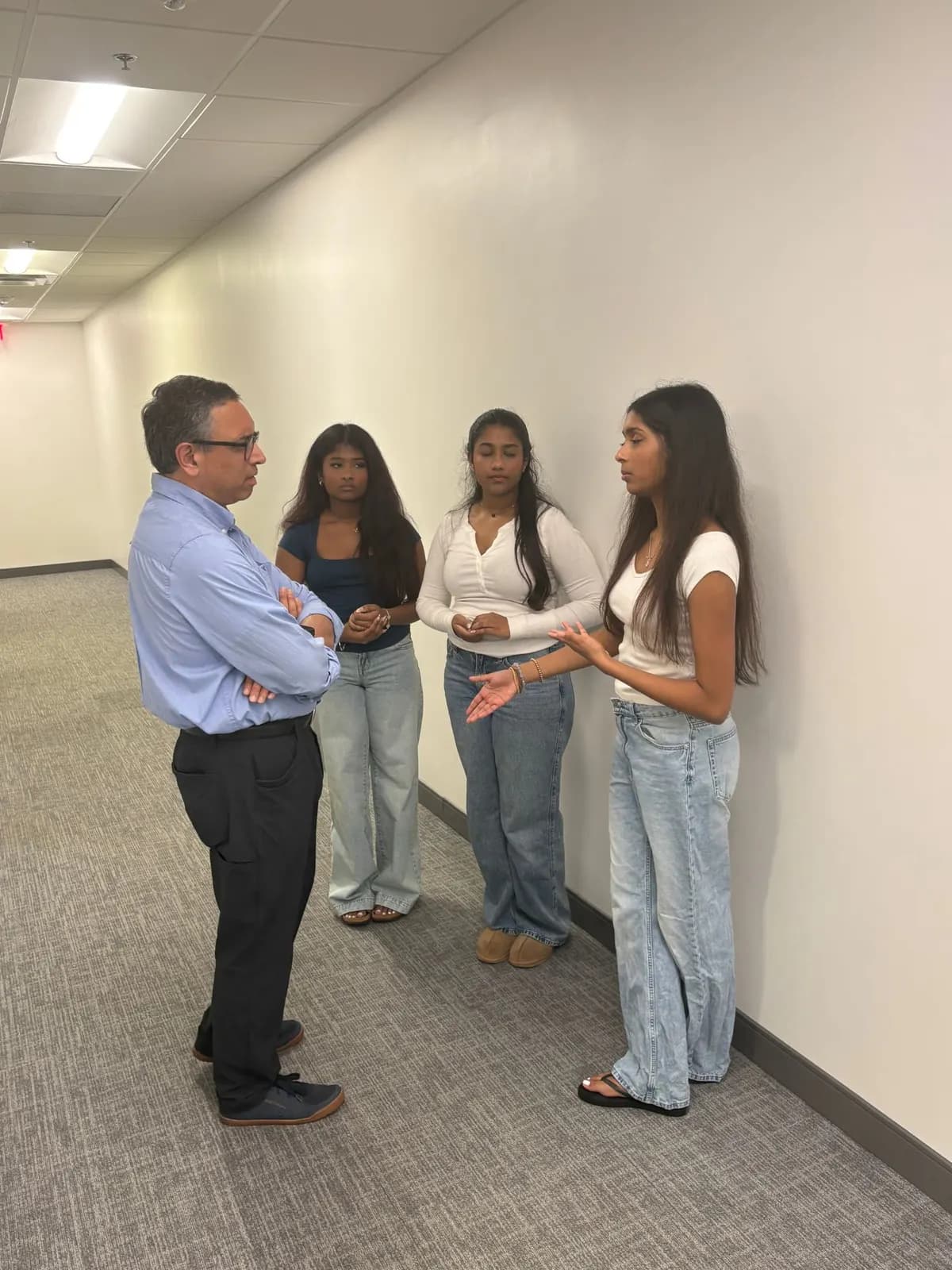 Three students in conversation with a visiting founder in the corridor outside the room