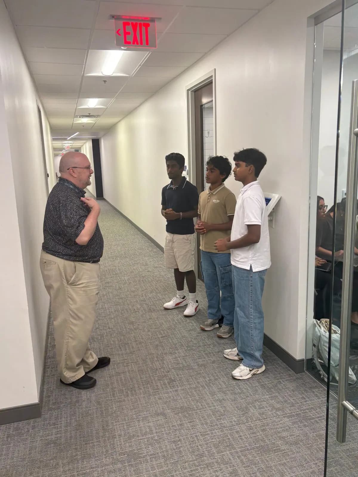 Three students talking with a visiting operator outside the session room